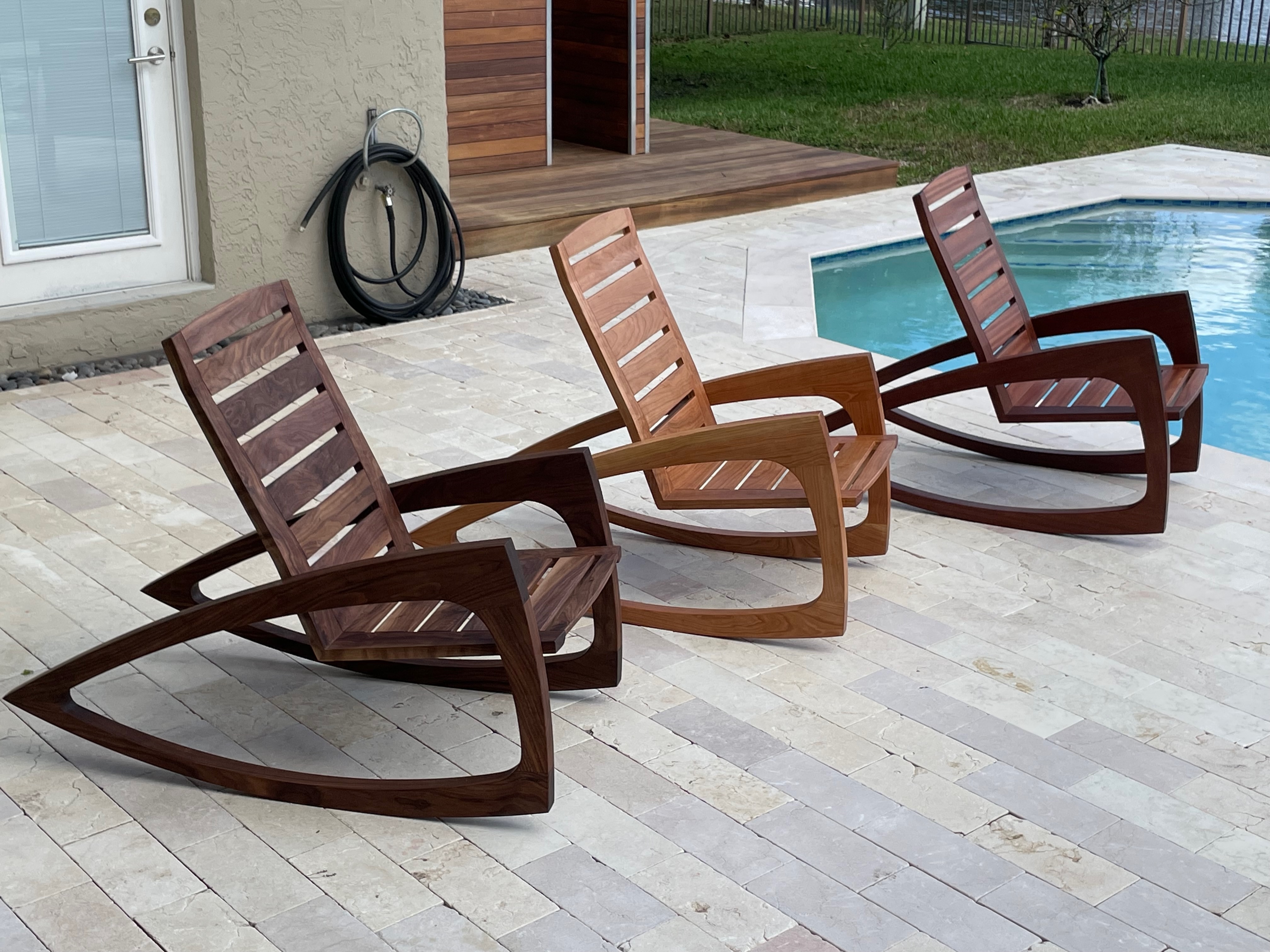 Three solid wood rocking chairs poolside