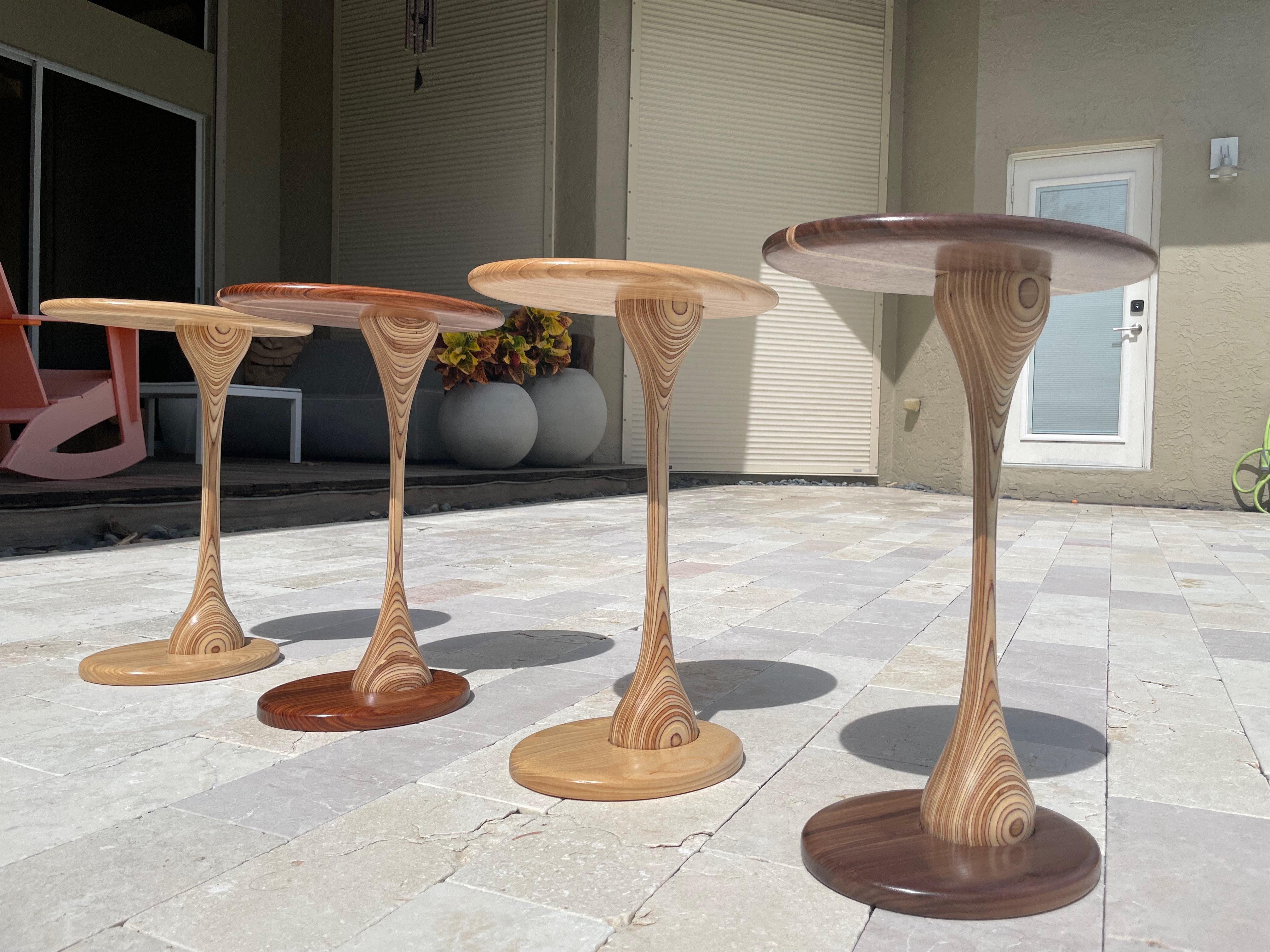 Four sculptural tulip pedestal tables in different wood species